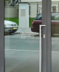 Openingstijden in wit vinyl aan de buiten zijde van een voordeur.